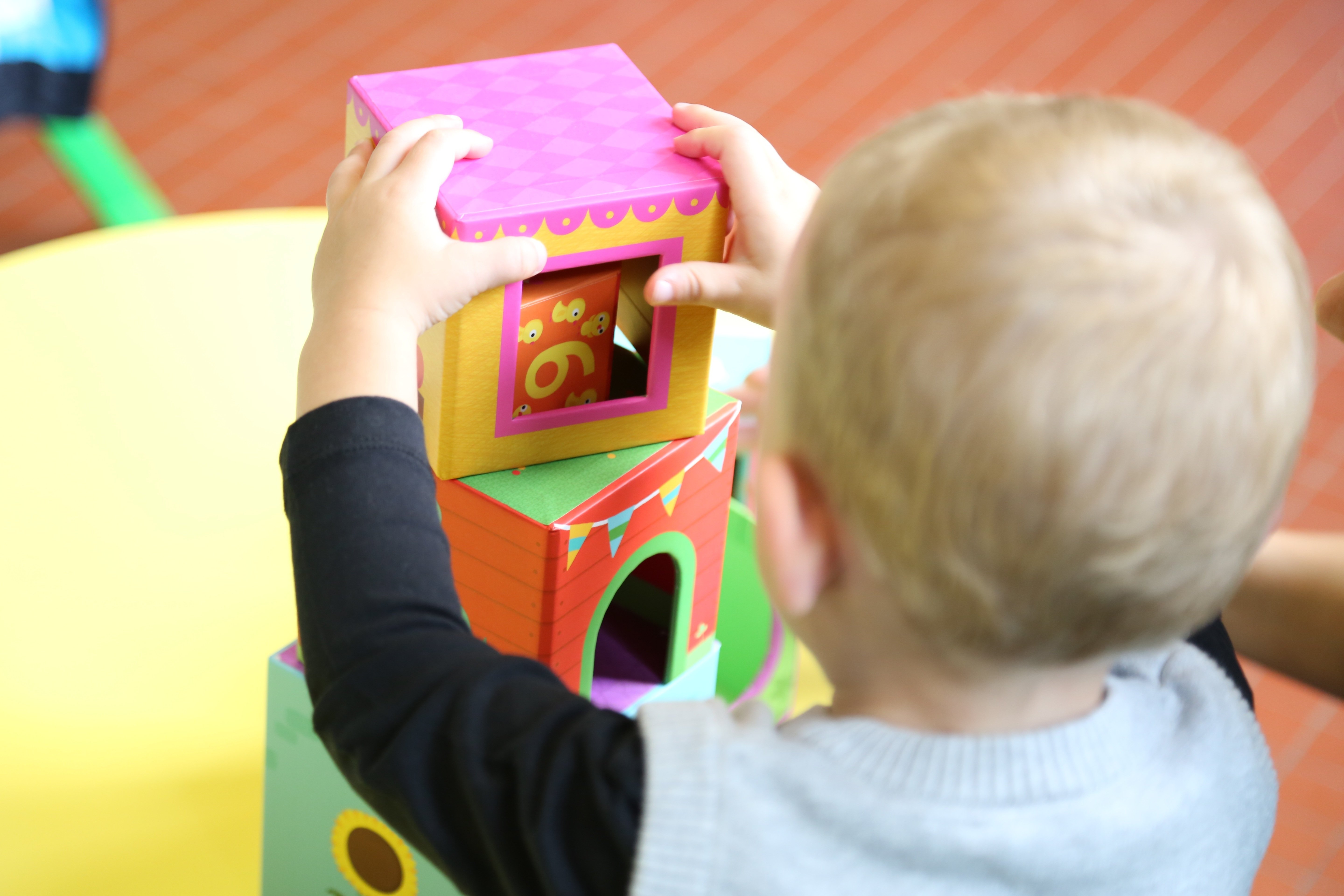 Kind stapelt Bunte Bausteine, während Hausregeln für Kinder im Alltag Struktur geben