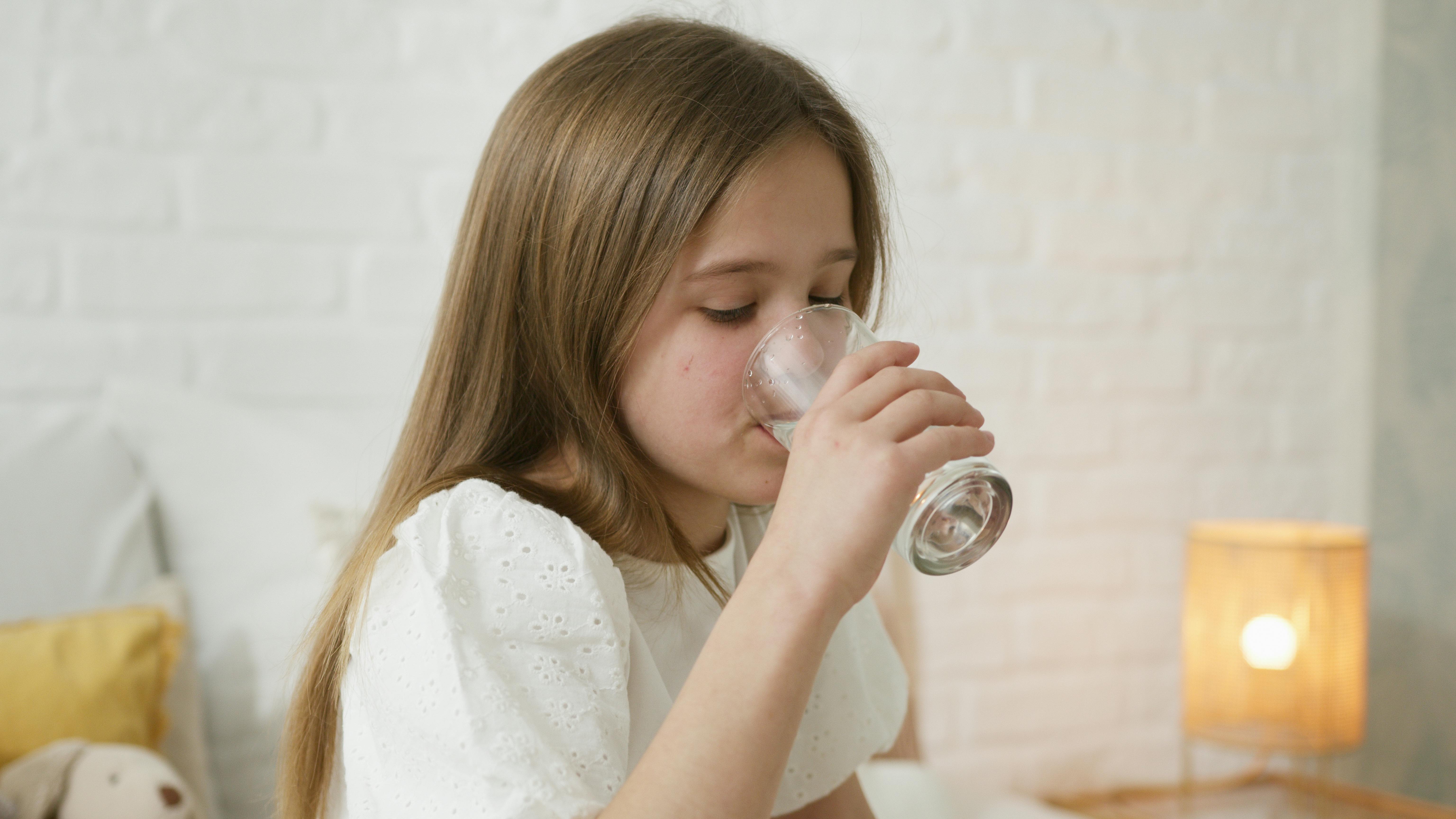 Kind trinkt Wasser zu Hause bei Anzeichen von Dehydrierung bei Kindern in Berlin