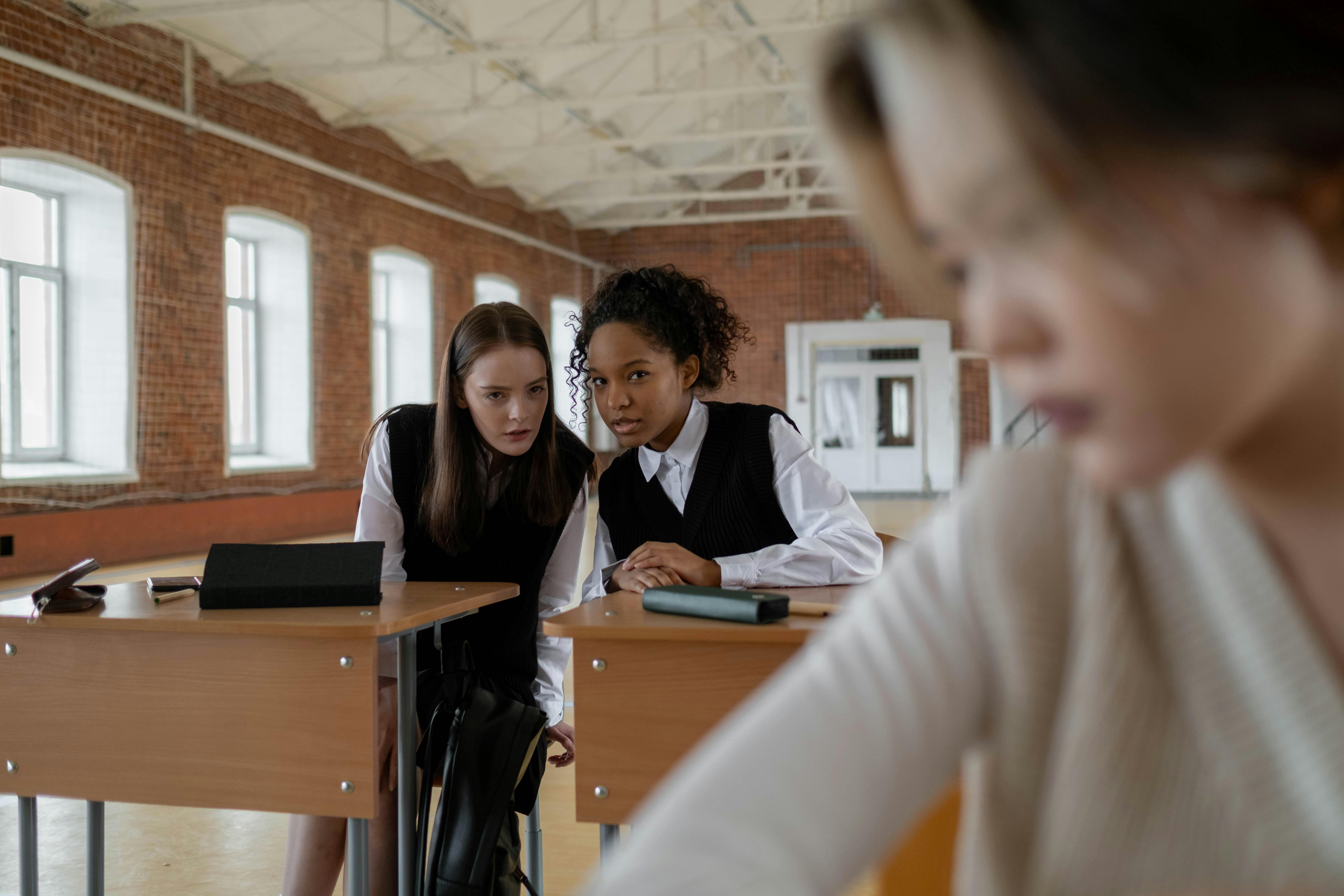 Schülerinnen tuscheln im Klassenzimmer als Zeichen für Gewalt in der Schule in Berlin